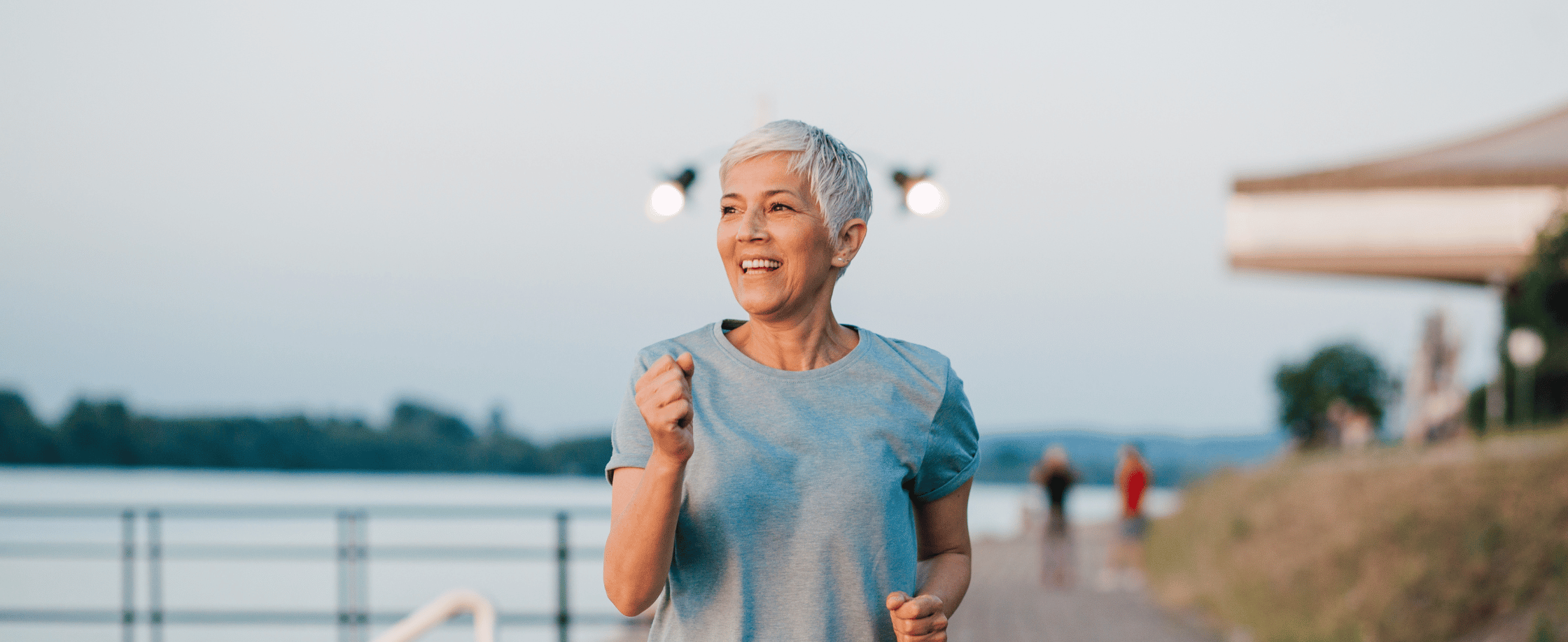 Older woman running outdoors while smiling—representing the strength and energy possible with chair yoga for seniors.