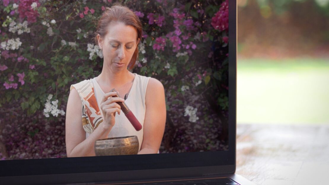 Online yoga teacher leading a traditional yoga class on screen with student following at home