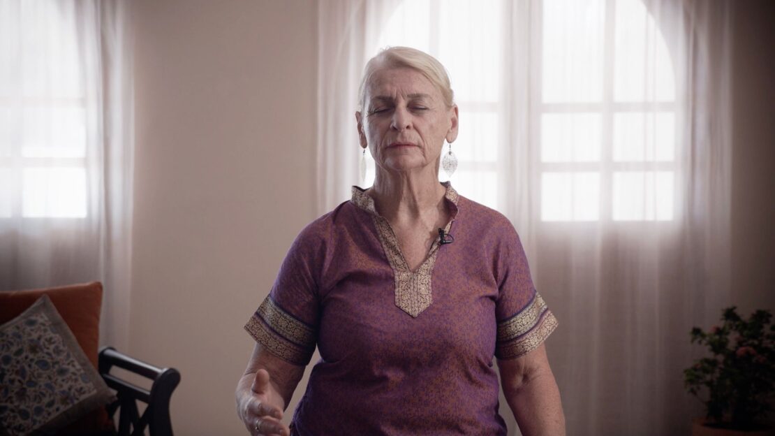 Woman in meditation or pranayama with eyes closed, sitting peacefully in a softly lit room for International Yoga Day