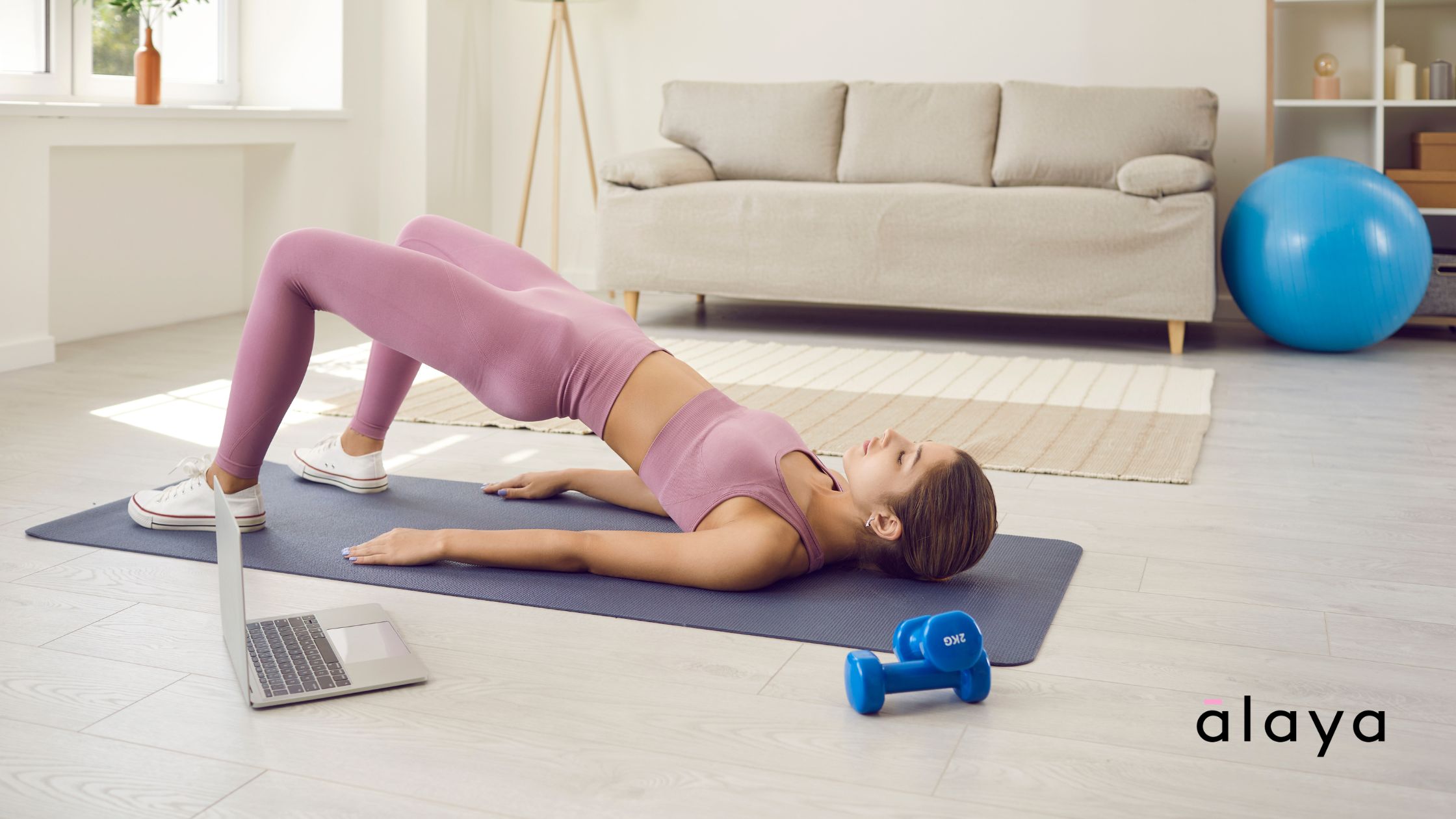 Laptop screen showing an online Pilates class with an instructor demonstrating a pose
