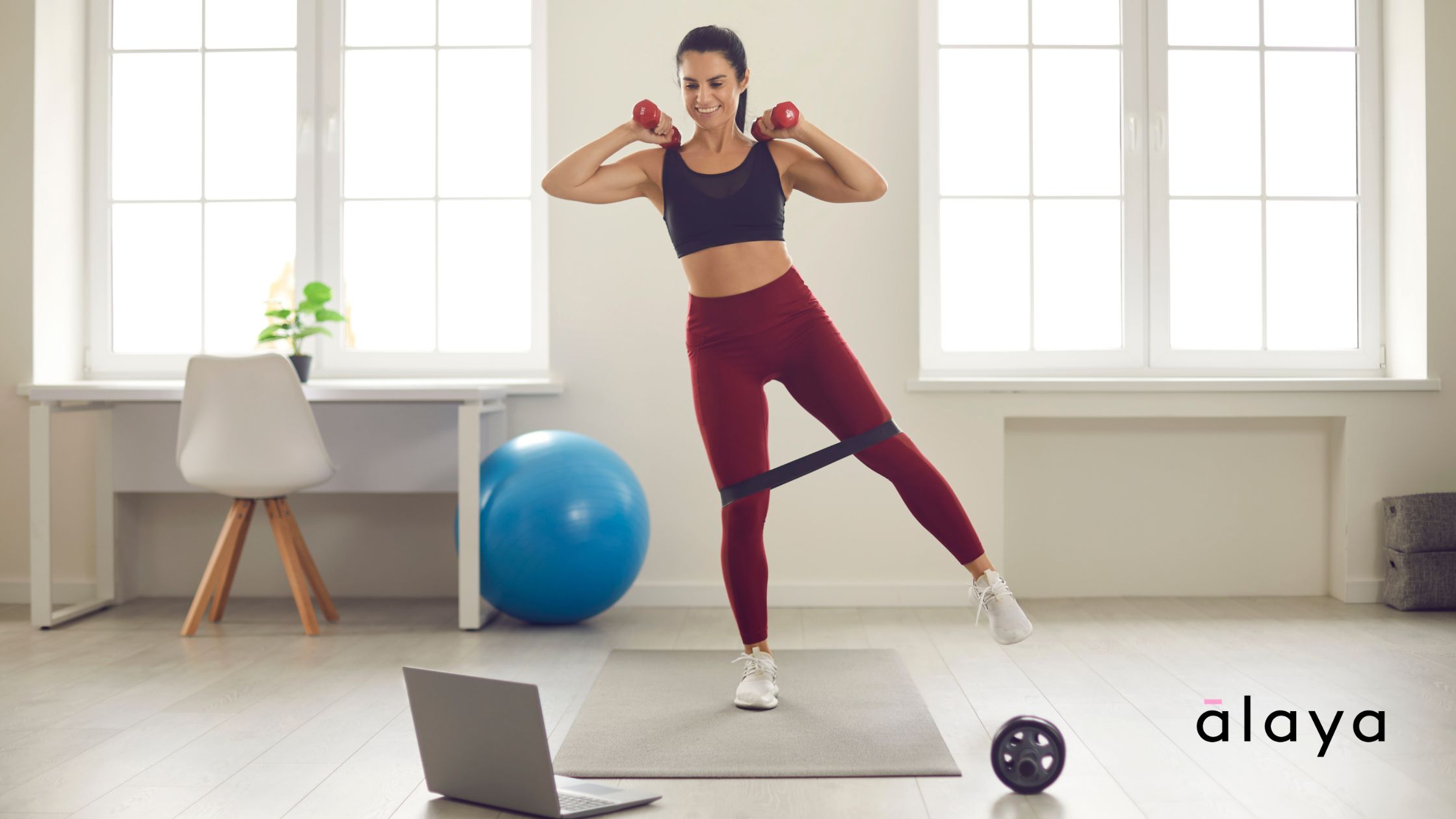 Woman doing Pilates on a mat at home while following an online class on her laptop