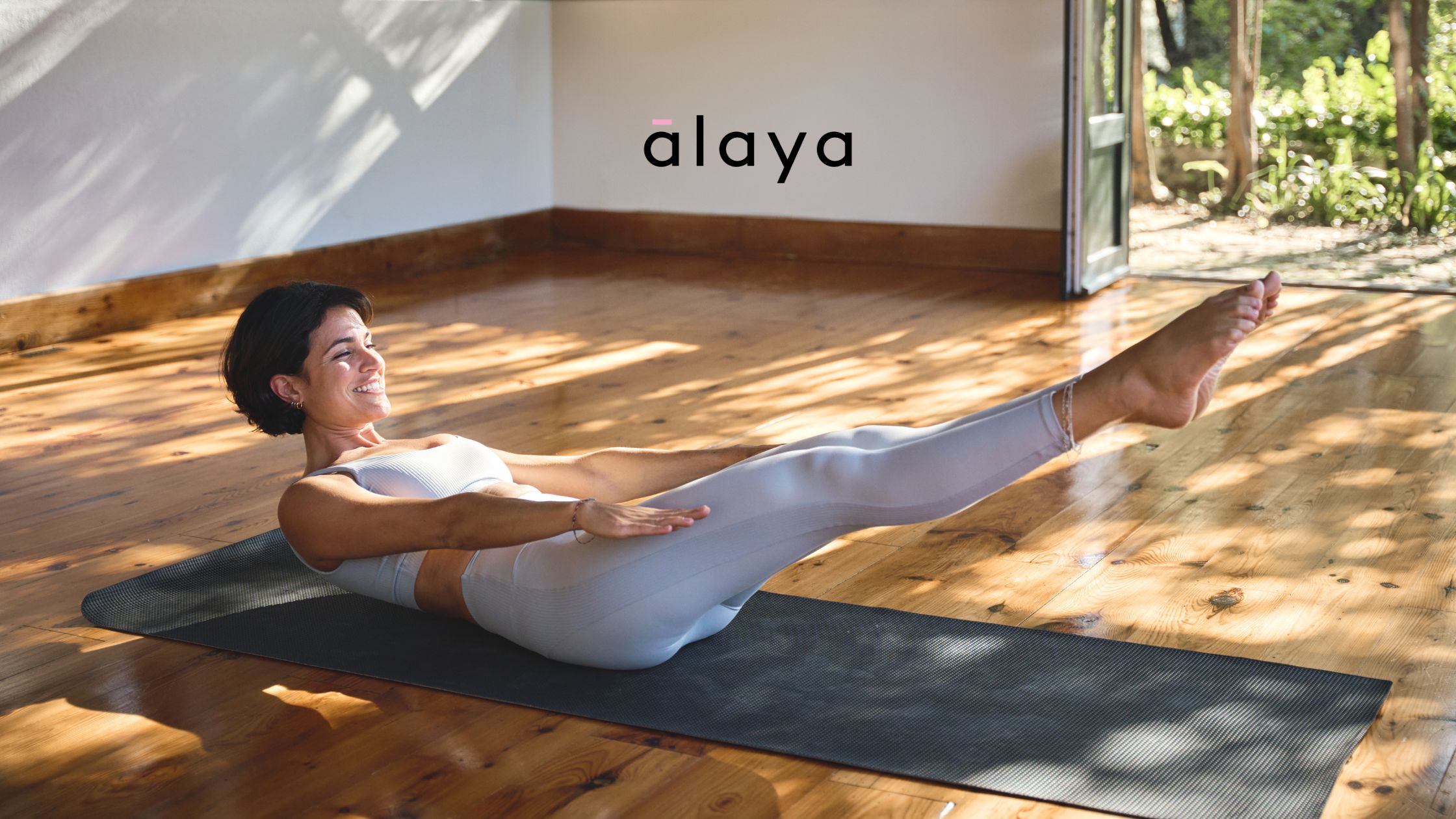 Smiling woman in activewear practising Pilates at home on a yoga mat, representing beginner-friendly home Pilates